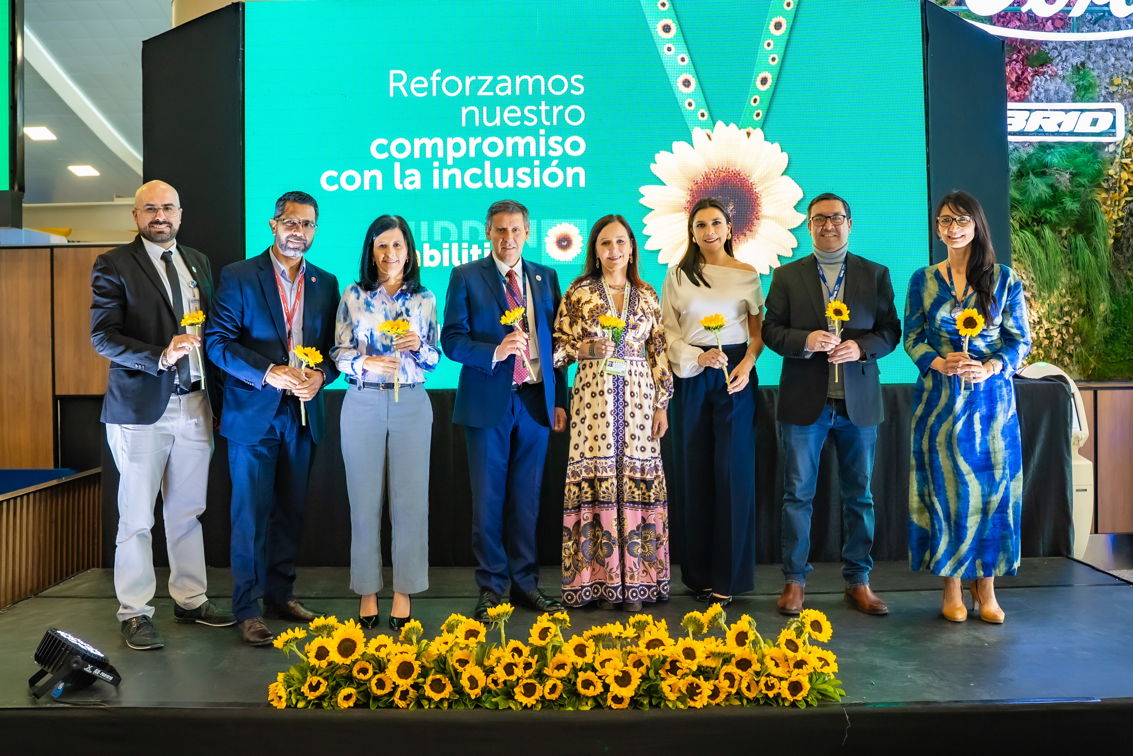 A group of Mariscal Sucre International Airport's executive board holding sunflowers with an image of the programme in the background.